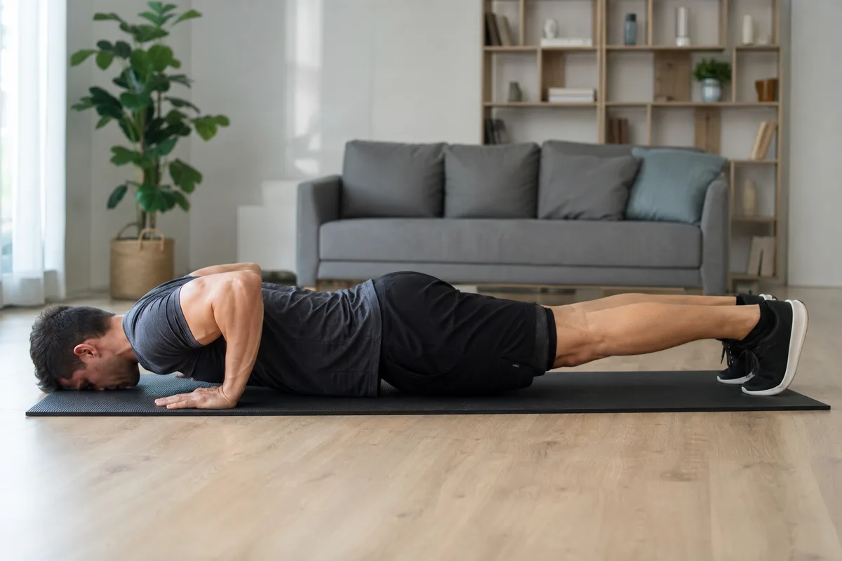 Homme en position de pompes sur un tapis de sport dans un salon, vu de profil